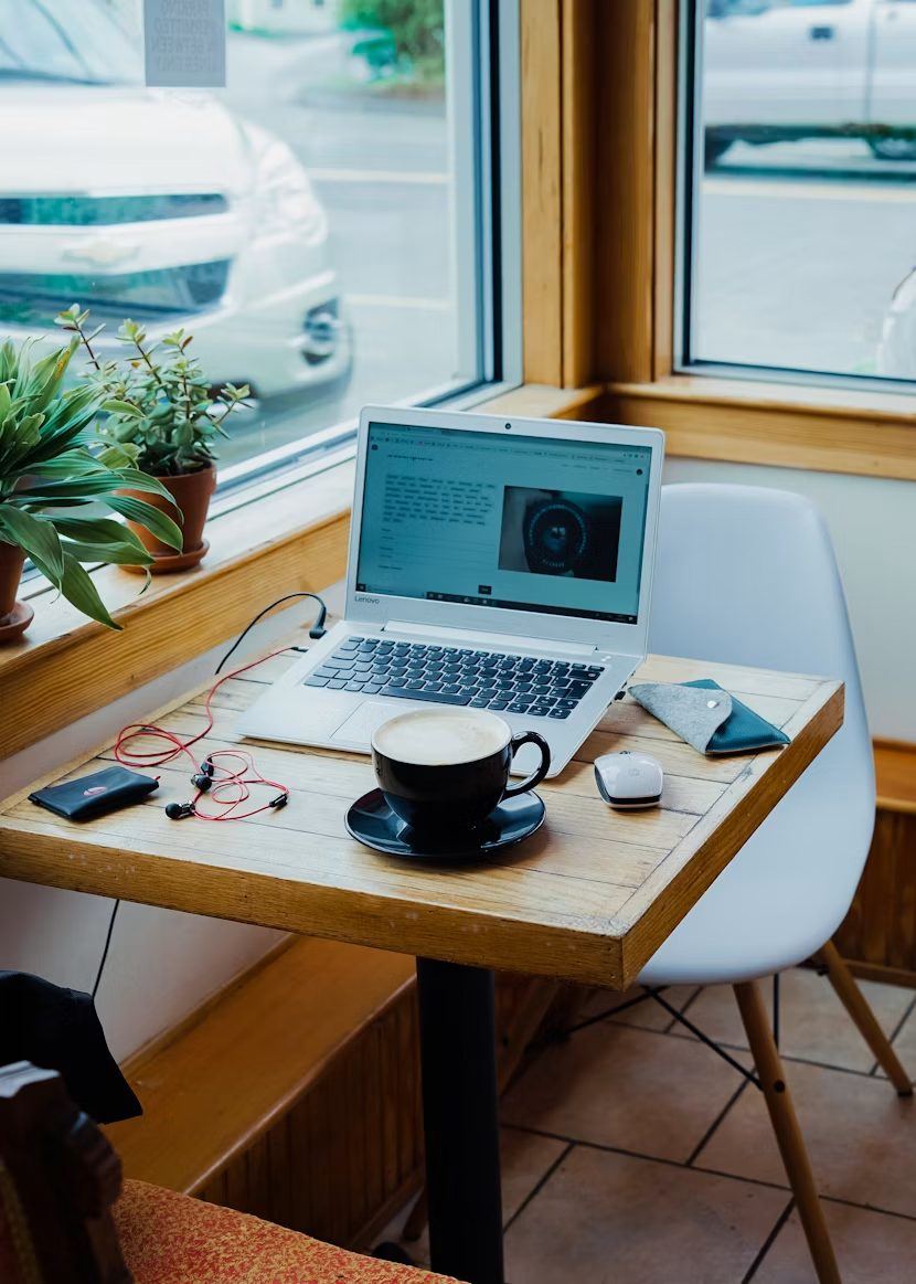 Person working on a laptop in a cafe representing the approachable way Optireach works with small business clients