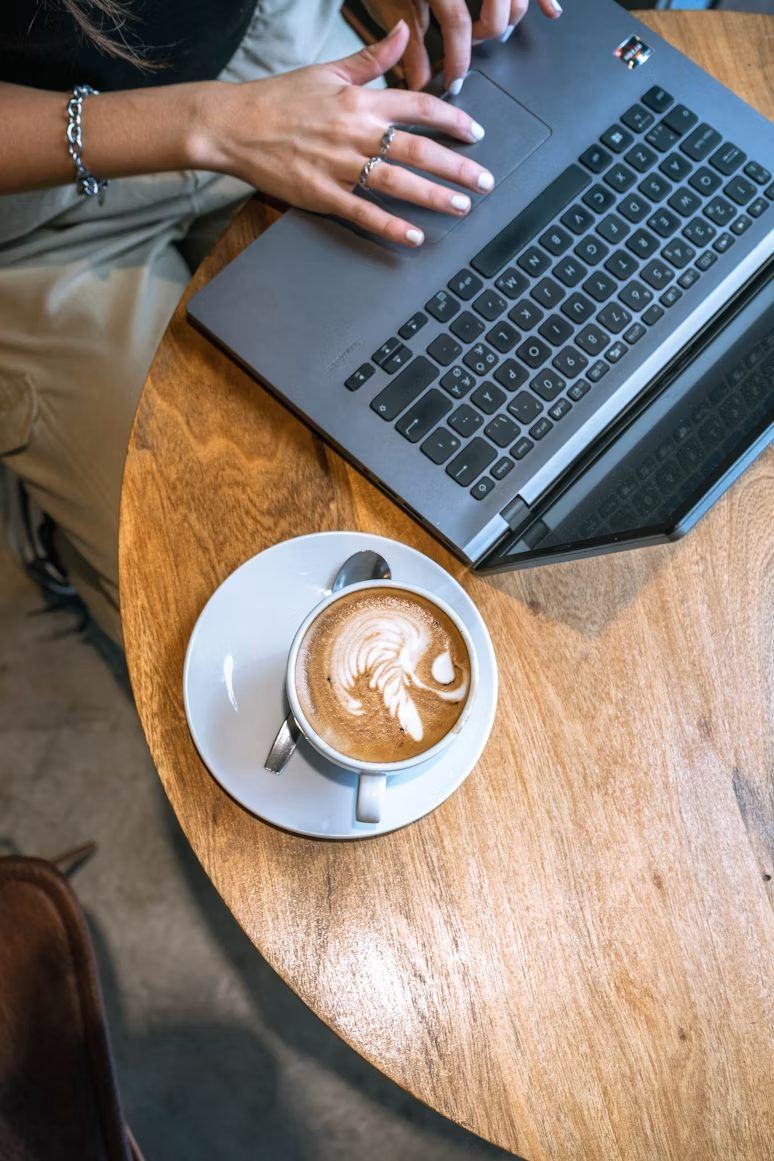 Person working on a laptop with coffee — representing the flexible way Optireach delivers SEO services for small businesses