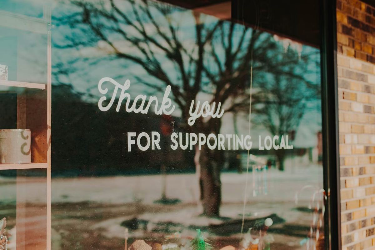 Shop window sign saying Thank You For Supporting Local — representing the local businesses Optireach helps grow online through SEO